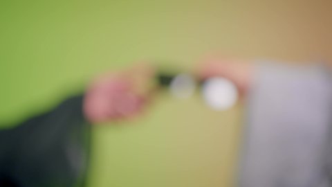 سيدة اماراتية تقوم بأخذ النظارة من صديقتها، عرض احدث موديلات النظارات الشمسية، تصوير مقرب لأيدي إمرأة عربية خليجية سعودية ترتدي العباءة تقوم بالتسويق للمنتجات المحلية، الاهتمام بالمظهر الخارجي والاناقة الشخصية، خلفية ملونة