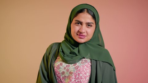 العروض الإعلانية التسويقية للمنتجات المحلية، الأناقة والاهتمام بالمظهر الخارجي، سيدة اماراتية تقوم بعرض احدث موديلات النظارات الشمسية، اتباع آخر صيحات الموضة, تصوير مقرب لإمرأة عربية خليجية سعودية مبتسمة ترتدي الحجاب والعباءة تقوم بوضع النظارة، خلفية ملونة