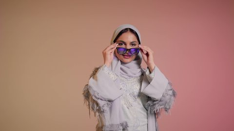عرض احدث موديلات النظارات الشمسية، متابعة آخر صيحات الموضة, تصوير مقرب لإمرأة عربية خليجية سعودية مبتسمة ترتدي الحجاب والعباءة تقوم بوضع النظارة، الأناقة والاهتمام بالمظهر الخارجي، سيدة اماراتية تقوم بالعروض الإعلانية التسويقية للمنتجات المحلية، خلفية ملونة