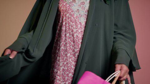 الاُثر الايجابي للتسوق على نفسية النساء، الاستفادة من العروض والتخفيض الموسمي، شراء الهدايا والمستلزمات، تصوير مقرب لامرأة عربية خليجية سعودية ترتدي العباءة والحجاب تحمل بيديها أكياس ملونة، سيدة اماراتية تمسك الحقائب بإيماءات السرور، خلفية ملونة