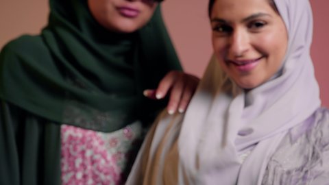 سيدتان عربيتان خليجيتان امراتيتان ترتديان العباءه تنظران الي الكاميرا بثقه وثبات, ايماءات  الانوثه والدلال،  سيده عربيه خليجيه سعوديه تمسك بيدها الهاتف المحمول بشاشه خضراء فارغه ، كروما