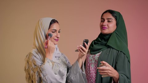 التعطر والتطيب بالعطر,  استخدام مستحضرات التجميل والمكياج للتزيين, امرأة عربيه خليجيه اماراتيه تقوم بالاستعداد والتحضر للذهاب برفقة صديقتها, تعابير السعادة والسرور