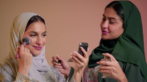 التعطر والتطيب بالعطر,  استخدام مستحضرات التجميل والمكياج للتزيين, امرأة عربيه خليجيه اماراتيه تقوم بالاستعداد والتحضر للذهاب برفقة صديقتها, تعابير السعادة والسرور