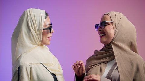الاهتمام بالأناقة والمظهر الخارجي، مفهوم النعومة والانوثة، الاعتزاز و الثقه بالنفس، بورترية مقرب لصديقتان عربيتان خليجيتان اماراتيان ترتديان العباءة الملونه و النظارات الشمسية، سيدتان سعوديتان تنظران الى الكاميرا بايماءات السعادة و السرور ، خلفية ملونه