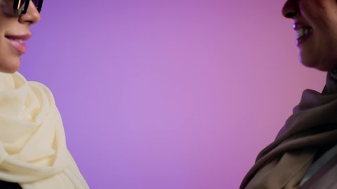 إيماءات السرور والثقة بالنفس،الأزياء العصرية التقليدية، الموضة والأناقة والاهتمام بالمظهر الخارجي، بورترية مقرب لشابتان عربيتان خليجتان اماراتيان محجبتان مبتسمتان ترتديان العباءة الملونه تنظران إلى الكاميرا ، عباءات خليجية نسائية عصرية، خلفية ملونه