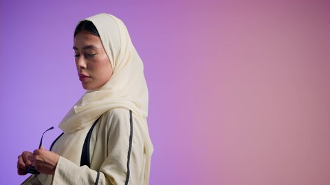 مفهوم النعومة والشياكة والأنوثة، الموضة والأناقة والاهتمام بالمظهر الخارجي، بورترية مقرب لشابتان عربيتان خليجتان سعوديتان محجبتان مبتسمتان ترتديان العباءة الملونه تنظران إلى الكاميرا بإيماءات السرور والثقة بالنفس،عباءات خليجية نسائية عصرية، صديقتان اماراتيان يقومان بقضاء أوقات ممتعة ، خلفية ملونه