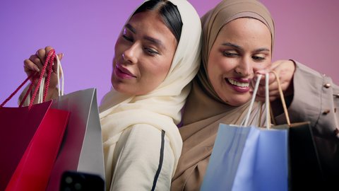 التقاط صور تذكاريه عن طريق الهاتف المحمول ، متعة التسوق مع الاصدقاء ،صديقتان سعوديتان تقوم بشراء الهدايا والمستلزمات ، استغلال الخصومات والتنزيلات ، أمرأتان عربيتان اماراتيان تحملان أكياس التسوق ،ايماءات وتعابير وجه تدل على السعادة