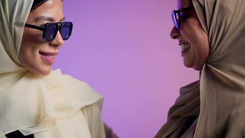 العلاقة الاخوية الايجابية، مفهوم الحب والمودة بين الاصدقاء، بورترية مقرب لإمرأة عربية خليجية اماراتية ترتدي الحجاب والعباءة الملونه برفقه صديقتها تنظر الى الكاميرا بإيماءات السعادة، شابتان سعوديتان ترتديان النظارات الشمسية تقضيان أوقات ممتعة ومسلية، ، خلفية ملونه