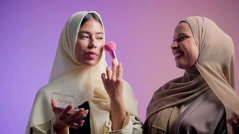 العناية بالجمال والمظهر الخارجي, استخدام المساحيق التجميلية, بورتريه مقرب لصديقتان عربيتان خليجيتان اماراتيان يقومان بالتزين و التجمل, الأنوثة والاهتمام بالجمال، خلفية ملونه