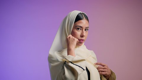 مفهوم العناية بالمظهر الخارجي، الاهتمام بالموضة والأناقة, تصوير لامرأة عربية خليجية إماراتية ترتدي العباءة الملونه تنظر بثقه و اعتزاز بالنفس , شابة سعودية تنظر إلى الكاميرا بإيماءات الدلع و الانوثه, خلفية ملونه