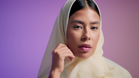 الاهتمام بالموضة والأناقة, مفهوم العناية بالمظهر الخارجي, تصويرمقرب لامرأة عربية خليجية إماراتية ترتدي العباءة الملونه تنظر بثقه و اعتزازبالنفس , شابة سعودية تنظر إلى الكاميرا بإيماءات الدلع و الانوثه, خلفية ملونه