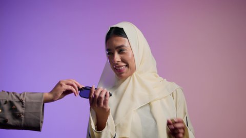 إيماءات الانوثة والجمال, الاستمتاع بإمتلاك اكسسوارات عصرية, مفهوم الموضة والاناقة ، سيدة اماراتية ترتدي عباءة أنيقة ونظارة سوداء،  تصوير لإمرأة عربية خليجية سعودية محجبة تقوم بتجربة النظارات الشمسية الجديدة، الاهتمام بالمظهر الخارجي ، خلفية ملونة