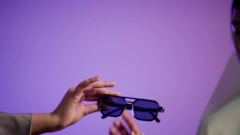 مفهوم الموضة والاناقة ، سيدة اماراتية ترتدي عباءة أنيقة ونظارة سوداء معاصرة،  تصوير لإمرأة عربية خليجية سعودية محجبة تقوم بتجربة النظارات الشمسية الجديدة، الاهتمام بالمظهر الخارجي ، إيماءات الانوثة والجمال, خلفية ملونة