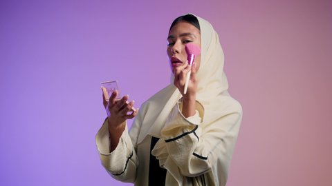 التسويق لمنتجات التجميل ، مفهوم الانوثه والاهتمام بالمظهر الخارجي، مكياج وميكاب تتوريال ، تصوير لفتاه عربيه سعودية خليجيه ترتدي العباءة والحجاب تحمل بيدها فرشاة توريد الخدود ، سيدة اماراتية تستخدم أدوات تجميل نسائيه عصريه، صالون نسائي راقي، خلفيه ملونه
