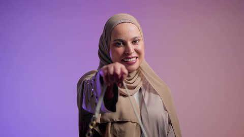 تصوير مقرب لشابة عربية سعودية خليجية محجبة تحمل بيدها حقيبة بإيماءات السعادة، عرض موديلات حقائب عالمية فاخرة، أزياء واكسسوارات نسائيه ، سيدة اماراتية ترتدي العباءة الخليجية العصرية ، مفهوم الموضة والأناقة