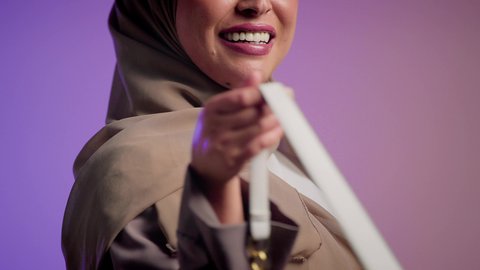 Women's fashion and accessories, display of luxury international handbag models. Close-up of a veiled young Saudi Arabian Gulf woman holding a bag with happy gestures. An Emirati woman wearing a modern Gulf abaya. The concept of fashion and elegance.