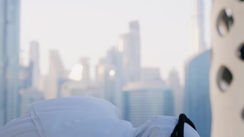 الاستمتاع بالمشروبات الساخنة، تصوير مقرب لرجل عربي خليجي اماراتي يرتدي الكندورة والغترة البيضاء يقوم بشرب القهوة في المقهى، قضاء وقت الفراغ باحتساء المشروب المفضل، تناول الأعشاب الدافئة، الأبراج وناطحات السحاب في الامارات