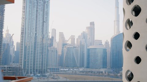 Viewing happy news, chatting and conversations on social media, a modern and advanced technical device, communicating with family and friends via mobile, a close-up of an Emirati Gulf Arab man wearing a kandura using a mobile phone, towers and skyscrapers in the Emirates