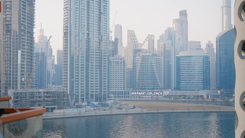 تعابير السعادة والسرور، دردشة ومحادثات عبر مواقع السوشال ميديا، جهاز تقني حديث ومتطور، التواصل مع الاهل والاصدقاء عبر الجوال، تصوير مقرب لرجل عربي خليجي اماراتي يرتدي الكندورة يقوم باستخدام الهاتف المحمول، الأبراج وناطحات السحاب في الامارات