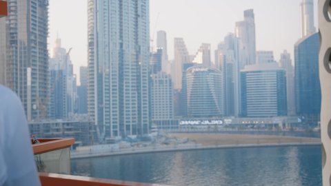 مشاهدة الأخبار السعيدة، دردشة ومحادثات عبر مواقع السوشال ميديا، جهاز تقني حديث ومتطور، التواصل مع الاهل والاصدقاء عبر الجوال، تصوير مقرب لرجل عربي خليجي اماراتي يرتدي الكندورة يقوم باستخدام الهاتف المحمول، الأبراج وناطحات السحاب في الامارات