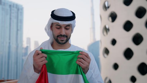 اليوم الوطني الاماراتي 1971، الاحتفال بذكرى تأسيس الاتحاد 2 ديسمبر في الخارج، حب الوطن والاعتزاز به، يوم العلم 3 نوفمبر، تصوير مقرب لرجل عربي خليجي اماراتي يرتدي الكندورة والغترة يقوم بتقبيل علم الامارات العربية المتحدة