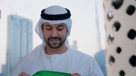حب الوطن والاعتزاز به، اليوم الوطني الاماراتي 1971، الاحتفال بذكرى تأسيس الاتحاد 2 ديسمبر في الخارج، يوم العلم 3 نوفمبر، تصوير مقرب لرجل عربي خليجي اماراتي يرتدي الكندورة والغترة يقوم بتقبيل علم الامارات العربية المتحدة