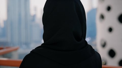 التواصل وتبادل الأحاديث والأخبار مع الأهل والأصدقاء، قضاء وقت ممتع في الخارج، ايماءات السعادة والسرور، اجراء مكالمة هاتفية عبر جهاز الجوال، تصوير مقرب لامراة عربية خليجية اماراتية ترتدي العباءة والحجاب تمسك بيدها الهاتف المحمول، استخدام جهاز تقني حديث ومتطور