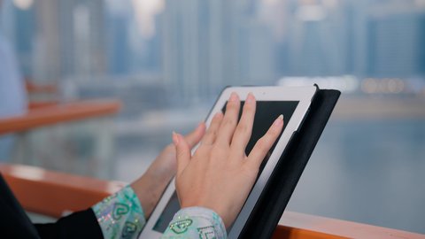 Working remotely abroad, managing business and completing required tasks via tablet, a female profession and job, a close-up of an Emirati Gulf Arab woman using a portable tablet, using a modern and advanced technical device