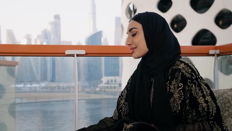 مطاعم وكافيهات  في الامارات العربية المتحدة، قضاء وقت الفراغ باحتساء المشروب المفضل, تناول الأعشاب الشتوية الدافئة، الاستمتاع بالمشروبات الساخنة، تصوير مقرب لامراة اماراتية ترتدي العباءة والحجاب تجلس على اريكة مريحة تقوم بشرب القهوة في المقهى