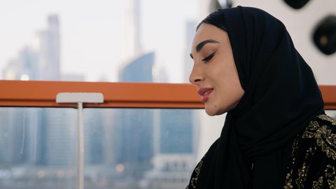 مطاعم وكافيهات  في الامارات العربية المتحدة، قضاء وقت الفراغ باحتساء المشروب المفضل, تناول الأعشاب الشتوية الدافئة، الاستمتاع بالمشروبات الساخنة، تصوير مقرب لامراة اماراتية ترتدي العباءة والحجاب تجلس على اريكة مريحة تقوم بشرب القهوة في المقهى