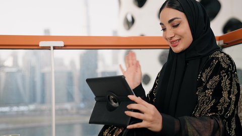 العمل عن بعد،  مهنة ووظيفة نسائية،  تصوير مقرب لإمرأة عربية خليجية اماراتية محجبة ترتدي عباءة سوداء تستخدم الحاسوب المحمول، استخدام جهاز تقني حديث ومتطور، ايماءات التركيز والاندماج، ادارة الأعمال وانجاز المهام المطلوبة