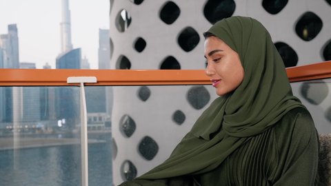 مطاعم وكافيهات  في الامارات العربية المتحدة، قضاء وقت الفراغ باحتساء المشروب المفضل, تناول الأعشاب الشتوية الدافئة، الاستمتاع بالمشروبات الساخنة، تصوير مقرب لامراة اماراتية ترتدي العباءة والحجاب تجلس على اريكة مريحة تقوم بشرب القهوة في المقهى