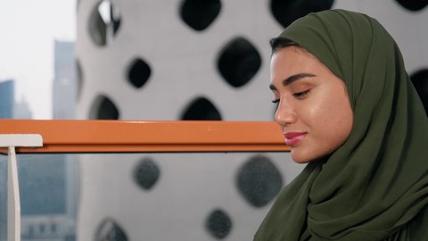 مطاعم وكافيهات  في الامارات العربية المتحدة، قضاء وقت الفراغ باحتساء المشروب المفضل, تناول الأعشاب الشتوية الدافئة، الاستمتاع بالمشروبات الساخنة، تصوير مقرب لامراة اماراتية ترتدي العباءة والحجاب تجلس على اريكة مريحة تقوم بشرب القهوة في المقهى