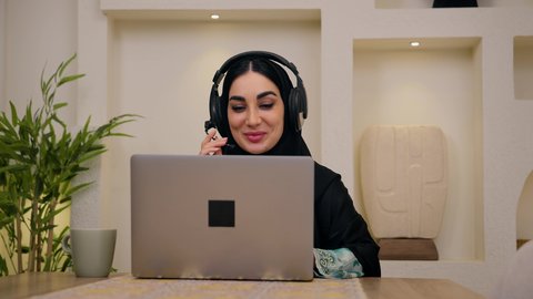 مشاهدة الافلام والمسلسلات ، تصفح التطبيقات والمواقع، الاستمتاع بالمشروبات الساخنه ، عقد إجتماع عمل عبر الإنترنت، الاستماع الى الموسيقي عبر سماعات الاذن ،تصوير مقرب لامرأة عربية خليجية سعودية ترتدي العباءه والحجاب تجلس في المنزل، جلسة عمل عن بعد، جلسات هادئة في المنزل، سيدة اماراتيه تستخدم جهاز الحاسوب المحمول