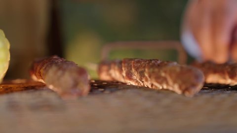 Fresh meat skewers and corn on the grill, preparing barbecue at gatherings, fun events and activities, cooperation and participation in preparing food, close-up photography of the barbecue process, turning the meat on the stove to ensure it is cooked well, outing and entertainment in a high-end tourist chalet during the holiday