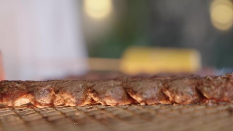 Preparing barbecue at gatherings, fun events and activities, cooperation and participation in preparing food, close-up photography of the barbecue process, turning the meat on the stove to ensure it is cooked well, fresh meat skewers on the grill, outings and entertainment in a high-end tourist chalet during the holiday