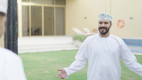 Handshake gestures and Islamic greetings between friends, a close-up of two Omani Gulf Arab men in a tourist chalet in Oman, outdoor seating, a family session, conversations and discussions, visits to family and relatives, communication and chatting