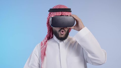 To interact and integrate with virtual reality, combine work with advanced technology, simulate the imaginary world, technological devices and modern technologies, a Saudi Arabian Gulf man wearing a thobe and a shemagh wearing 3D VR glasses
