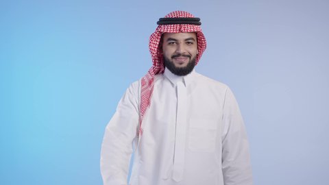 مفهوم لغة الجسد وتعابير الوجه, الاشارة بالإصبع الإبهامي علامة لايك, رجل عربي خليجي سعودي بشوش الوجه يرتدي ثوب أبيض مع شماغ وعقال و يقوم بعلامة الموافقة بالإبهام