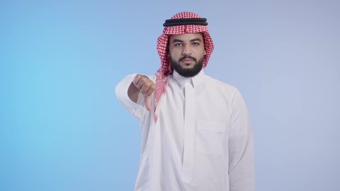 عدم الإعجاب وعدم قبول شيء ما، التقييم السلبي والفشل، رجل عربي خليجي سعودي يرتدي الزي التقليدي والشماغ يشير باصبع الإبهام لأسفل اشارة تدل على الرفض والإستياء وعدم الرضى