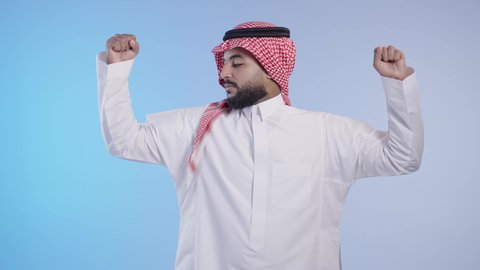 ممارسة الرياضه للحصول على جسم سليم, رجل عربي خليجي سعودي يرتدي الزي التقليدي والشماغ و ينظر الى عضلاته, إيماءات وجه ويدين تدل على القوه و الصحه الجسديه