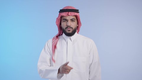 الهدوء والسكون وعدم الإزعاج, اشارات طلب السكوت والصمت، رجل عربي خليجي سعودي يرتدي الشماغ والثوب التقليدي ويضع أصبع السبابة على فمه بإيماءات وجه غاضبة