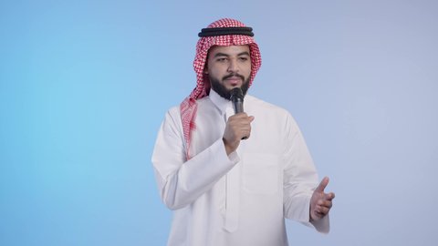 الاستمتاع بأداء المواهب الصوتية، رجل عربي خليجي سعودي  يرتدي الثوب التقليدي والشماغ يحمل بيده المايك، تسجيل مقطع صوتي، تقديم العروض المسرحية