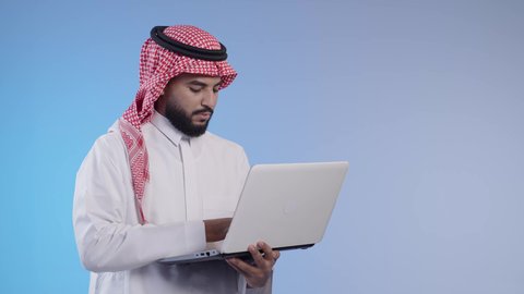 إدارة الأعمال عن بعد, رجل عربي خليجي سعودي يرتدي الشماغ والثوب التقليدي يقوم بانجاز المهام عبر الحاسب المحمول, استخدام الأجهزة والتقنيات الحديثة