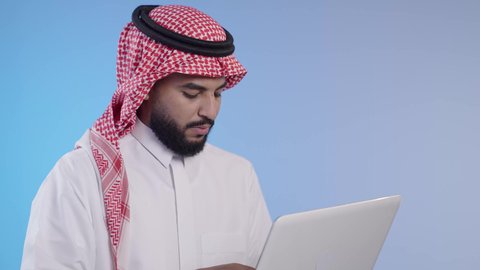 تصفح الانترنت وبرامج التواصل الاجتماعي, إستخدام الحاسوب المحمول في العمل، إدارة الأعمال عن بعد, رجل عربي خليجي سعودي يرتدي الشماغ والثوب التقليدي يقوم بانجاز المهام عبر اللابتوب