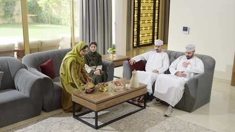 كرم الاستقبال والضيافة، اجتماع الأهل والأصدقاء في الهواء الطلق، قضاء وقت ممتع ومسلي مع مجموعة من الأصدقاء، أصدقاء عربيون خليجيون عمانيون بالزي التقليدي يشربون القهوة العربية ويتبادلون الأحاديث بإيماءات الاندماج، التنزه والتسلية والترفيه في شاليه سياحية في عمان