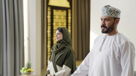 القاء التحية والسلام، التواصل الأسري والدفء الاجتماعي، ايماءات السعاده و السرور، الترحاب والكرم العربي، عائله عربيه خليجيه عمانيه ترتدي الزي التقليدي تقوم باستقبال الاصدقاء داخل غرفه المعيشه، التحدث و تبادل الاحاديث