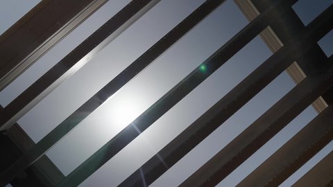 سقف خشبي في شاليه فاخر في سلطنة عمان، قرص الشمس المضيء في وسط السماء الزرقاء، قضاء وقت ممتع خارج المنزل