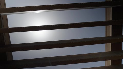 A wooden ceiling in a luxury chalet in the Sultanate of Oman, the shining sun disk in the middle of the blue sky, spending enjoyable time outside the house.