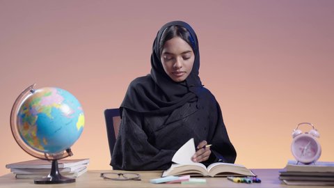 التزود بالعلم والمعرفة، قضاء وقت الفراغ بالتثقيف والتعلم، مفهوم محو الأمية، طالبة جامعية سمراء عربيه سعوديه ترتدي العباءه والحجاب تمارس هواية مطالعة الكتب المفيدة في وقت الفراغ، القراءه بإيماءات التمعن والتركيز